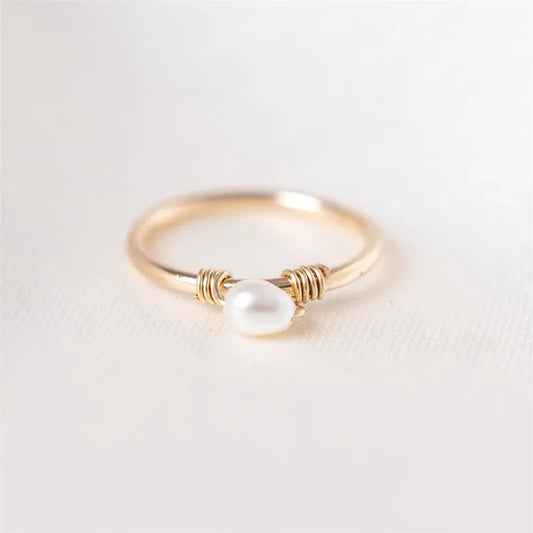 Gold ring with a pearl on a light gray background