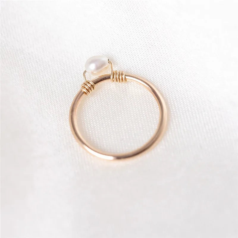 Gold ring with a pearl on a white fabric background