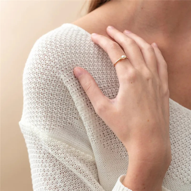 Person wearing a white knit sweater with a close-up of a hand touching the shoulder.