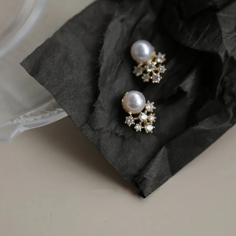 Pair of pearl earrings with gold accents on a black fabric surface