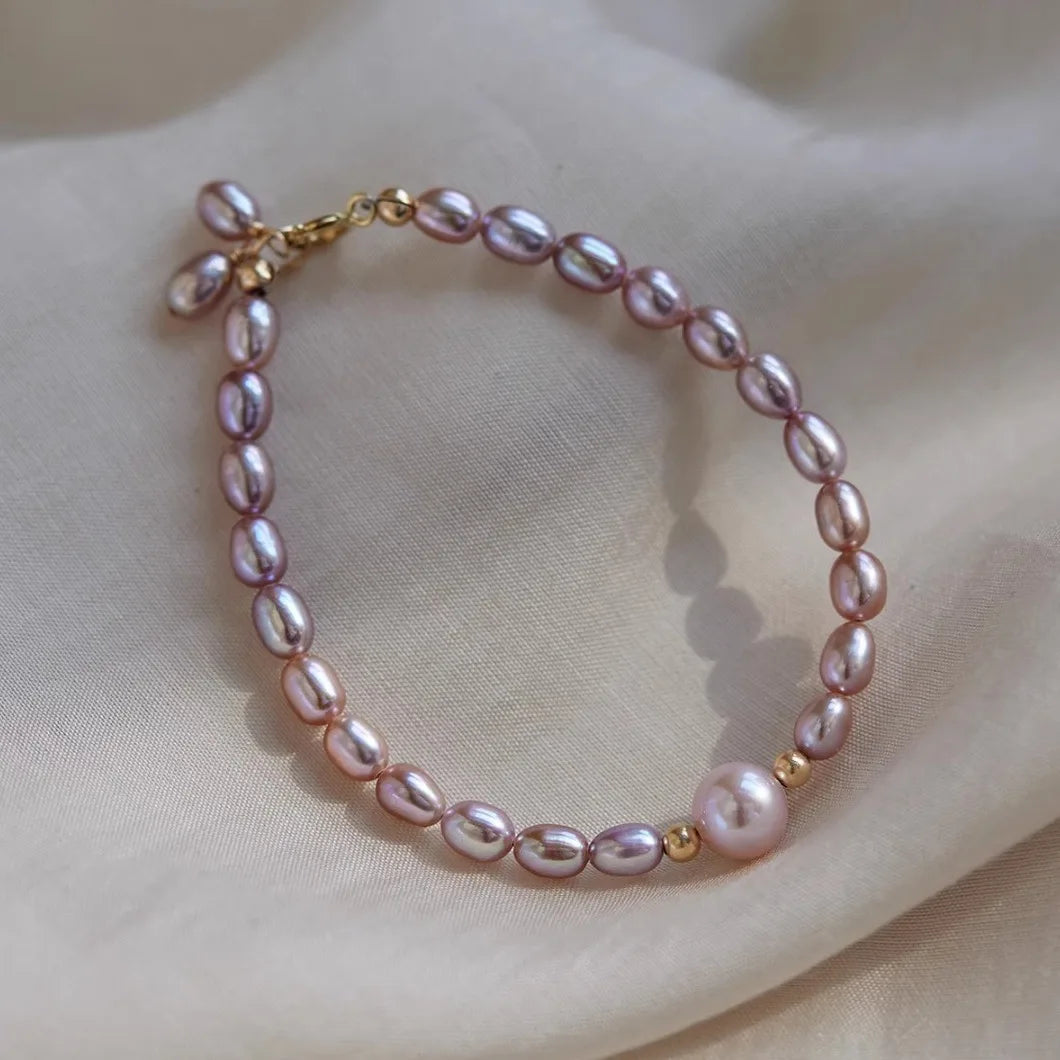 Pink pearl bracelet with gold accents on a beige fabric background