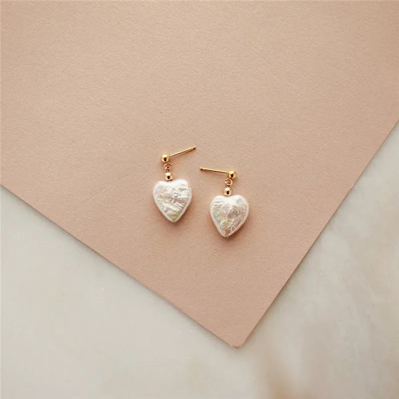 Heart-shaped earrings on a soft pink background