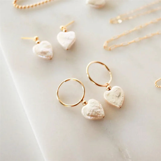 Gold heart-shaped earrings on a marble surface