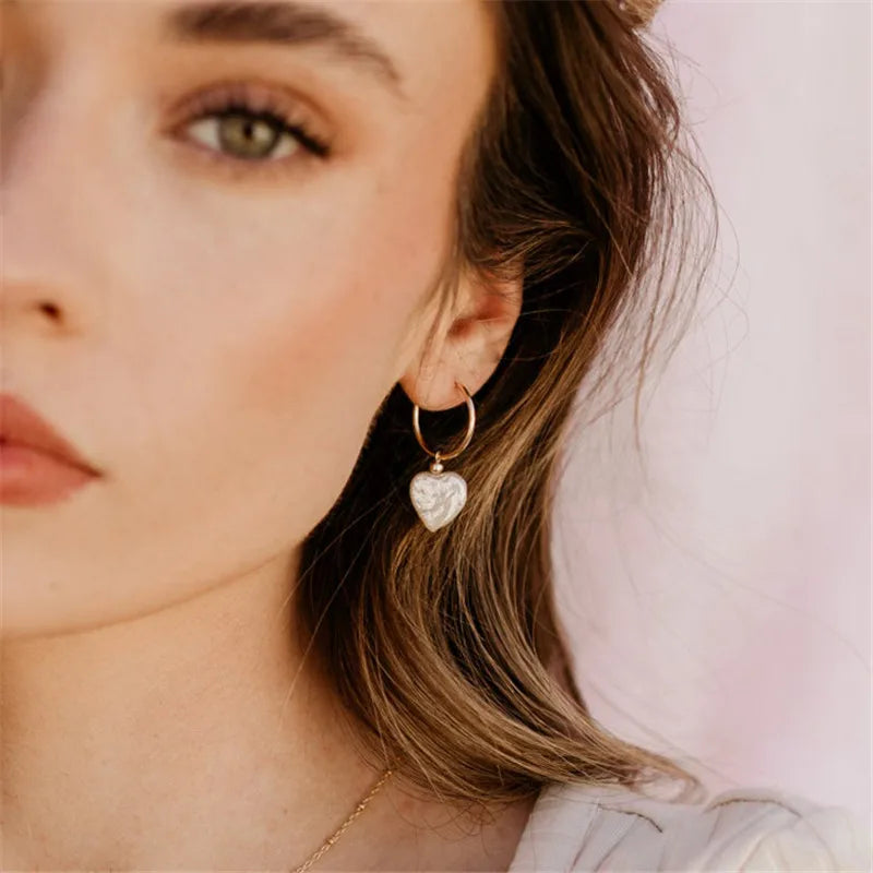 Close-up of a woman wearing a heart-shaped earring with a soft background